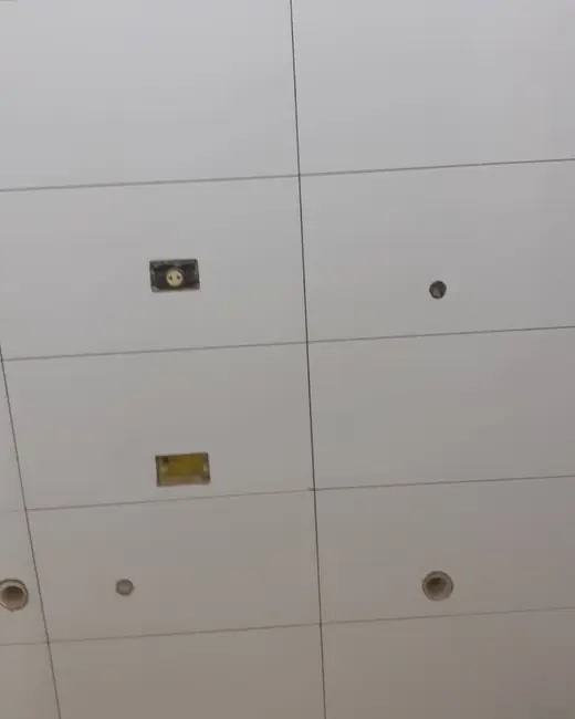 Parede revestida de azulejo branco, com os pontos de água e de luz no lugar